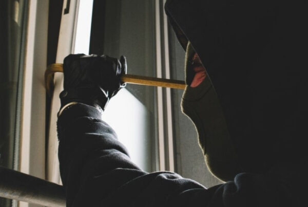 Afbeelding van een inbreker die met een koevoet een raam openbreekt.